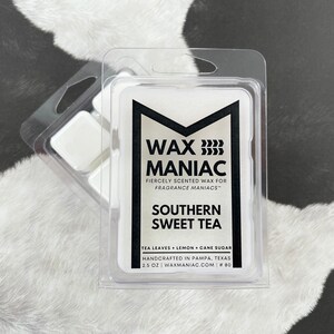 May include: A white wax melt in a clear plastic container with the text "WAX MANIAC" in black. The wax melt is scented with "Southern Sweet Tea" and has the ingredients "Tea Leaves + Lemon + Cane Sugar" listed below. The wax melt is handcrafted in Pampa, Texas and is 2.5 oz.