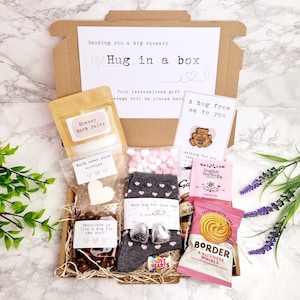 May include: A 'Hug in a Box' gift set, containing bath salts, chocolates, socks, tea, and biscuits. The brown box has a card that says "Hug in a box". A comforting gift.