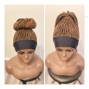 May include: A brown braided wig with a black headband. The wig is styled in a high bun on one side and a ponytail on the other.