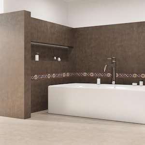 May include: A modern bathroom with a white rectangular bathtub, a silver faucet, and brown walls. Decorative tile with a floral pattern borders the tub. White soap dispensers and small containers are placed near the tub.