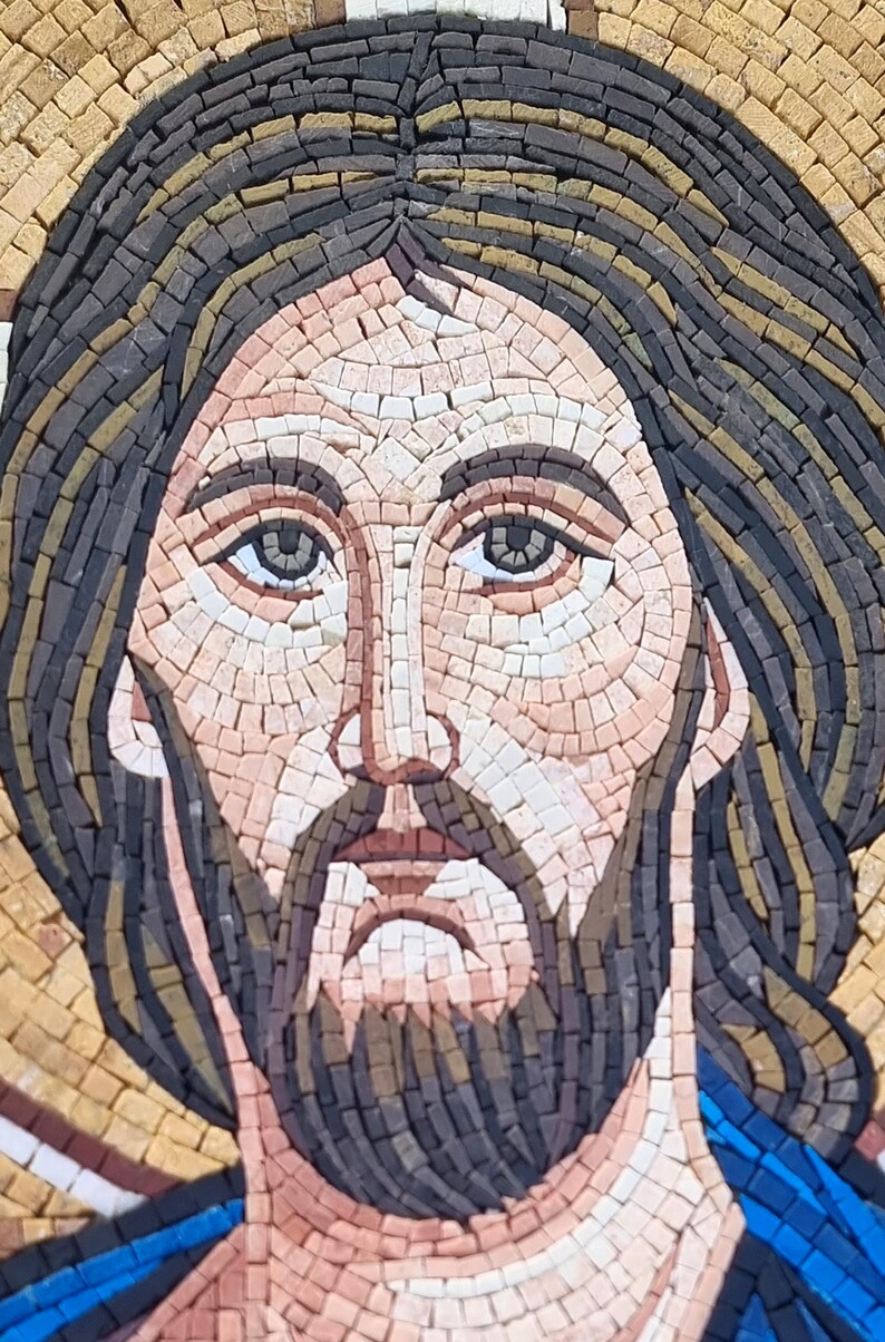 May include: Close-up of a mosaic portrait depicting a man with a beard and long hair. The mosaic is composed of small, rectangular tiles in shades of brown, beige, and blue. The man's face is detailed, with a serene expression.