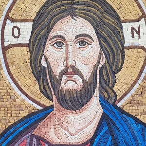 May include: Mosaic portrait of a man with a beard, wearing a blue and red robe, and a halo with the letters "O" and "N". The mosaic is made of small, colorful tiles, creating a detailed image. The background is a light brown color.