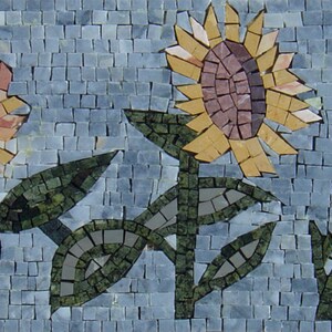 Può includere: Un'opera d'arte in mosaico di piastrelle che raffigura tre girasoli con foglie verdi su uno sfondo blu.
