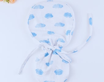 May include: White baby bonnet with blue watercolor cloud print. The bonnet has ties that can be tied under the chin.