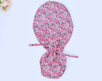 May include: A pink and green floral print fabric scrunchie with a gathered top and two long ties.