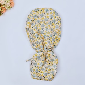 May include: A yellow and green patterned surgical scrub hat with the text "This close to losing it" repeated throughout the fabric.