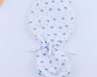 May include: A white fabric baby bonnet with a blue floral pattern. The bonnet has a drawstring closure.