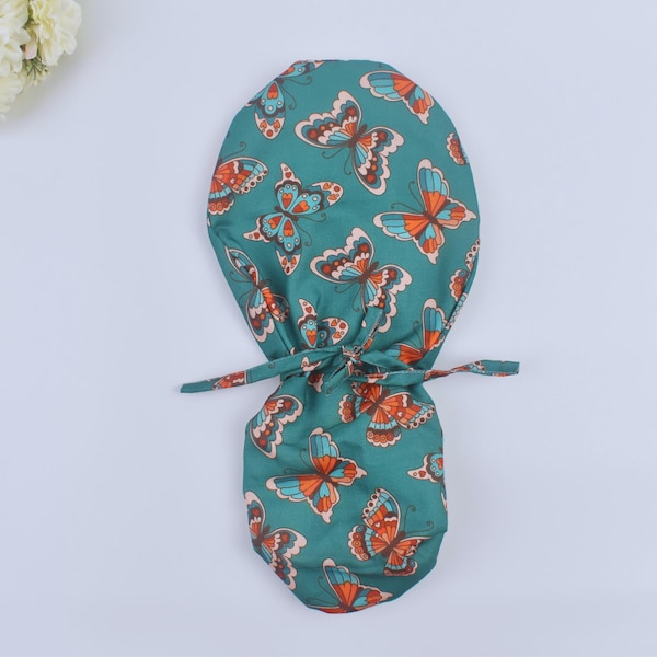 Vlinders op groene paardenstaart scrubmuts, operatiemuts dames. Met satijn gevoerde optie operatiemuts met paardenstaart. Met satijn gevoerde scrubmuts.