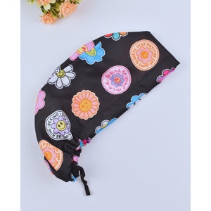 May include: Black scrub hat with a colorful floral and smiley face print. The hat has a drawstring and the text "Be Kind to Your Mind", "And Happy Always Stay Positive" and "Be Kind - Be Kind" is printed on the hat.