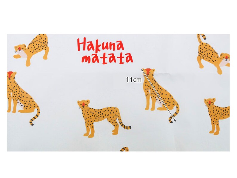 May include: White fabric with a repeating pattern of orange and black cheetahs. The text "Hakuna Matata" is printed in red letters. The fabric is 11 inches wide.