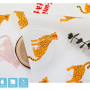 May include: White fabric with a repeating pattern of yellow and orange leopards. The fabric is waterproof and has UV protection. The fabric is also water-resistant and has a durable material.