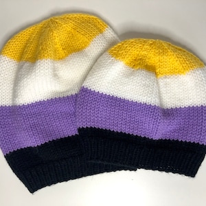 May include: Two knitted beanies in yellow, white, purple, and black stripes. The beanies are made with a soft, textured yarn.