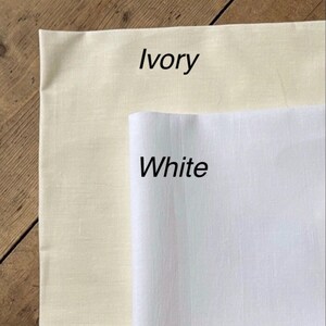 May include: Two fabric swatches, one ivory and one white, with the color names written below each swatch.