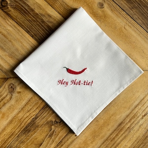 May include: White kitchen towel with red embroidery of a chilli pepper and the text "Hey Hot-tie!"