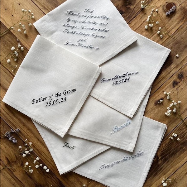 May include: A collection of five white fabric handkerchiefs featuring various embroidered messages in black and blue thread, including "Dad Thank you for walking by my side today and always," "Father of the Groom 25.05.24," "Grow old with me 03.05.24," "Brooke," "Jack," and "Keep your shit together."