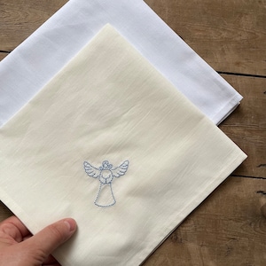 May include: A white cotton tea towel with a blue embroidered angel design.