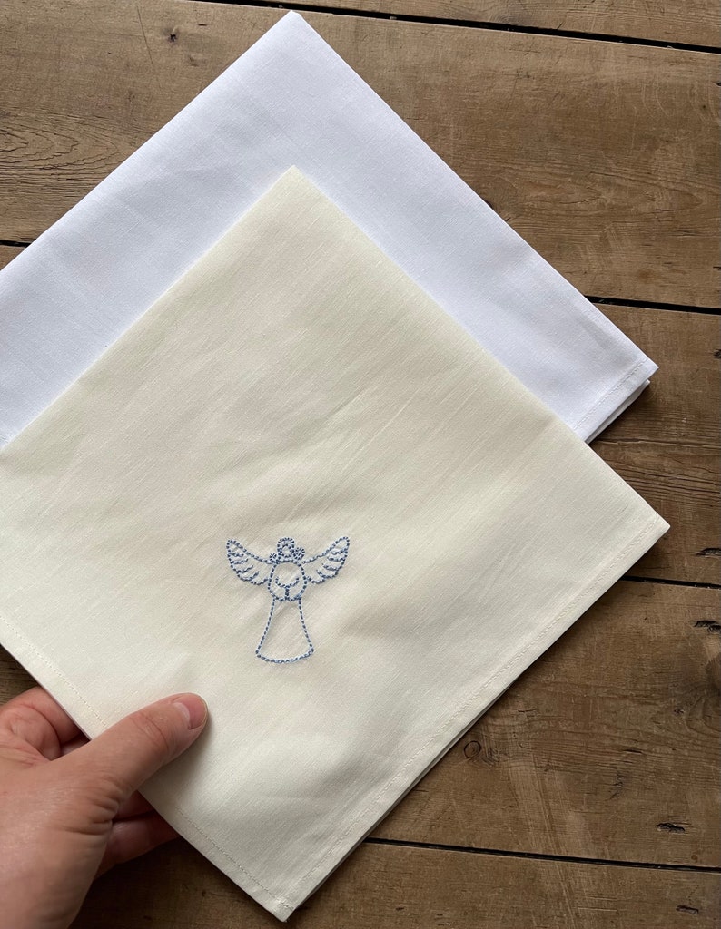 May include: A white cotton tea towel with a blue embroidered angel design.