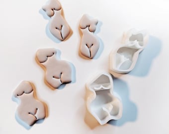 May include: Five white silicone molds of a female figure in various poses. The molds are used for making fondant or polymer clay figures.