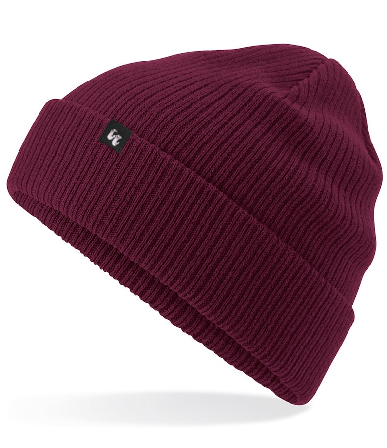 Burgundy organic cotton beanie hat with black fabric tag stitched to the cuff