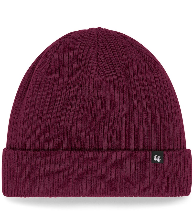 Front view of burgundy organic cotton beanie hat with black fabric tag stitched to the cuff