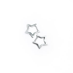 May include: Two silver-colored star-shaped earrings. The earrings are open in the center and have a five-point star design. The earrings are on a white background.