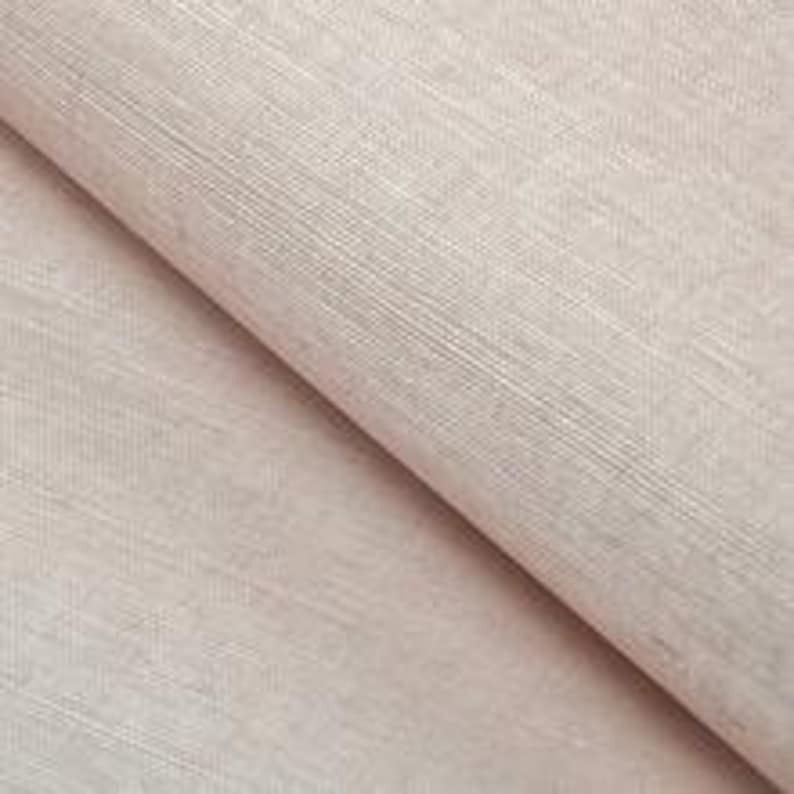 Op de afbeelding: Een close-up van een lichtbeige stof met een subtiele geweven textuur. De stof heeft een gladde, zachte uitstraling.