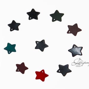 Op de afbeelding: Een verzameling van tien kleine stervormige bedels in diverse kleuren, waaronder rood, donkergroen, zwart en bruin, elk voorzien van een enkel gaatje voor bevestiging. De tekst "Lazypony" staat in de rechterbenedenhoek van de afbeelding.