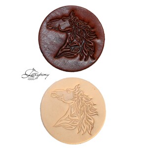 Peut inclure: Deux disques en cuir circulaires présentant un motif de tête de cheval en relief. Un disque est brun foncé et l'autre est de couleur beige naturel. Le texte "Lazypony" est imprimé en écriture noire entre les deux cercles en cuir.