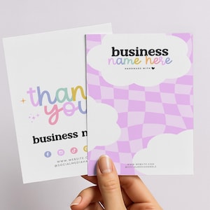 以下が含まれることがあります： 2つの名刺が手に持たれています。1つは「business name here」というテキストが入ったパステルチェック柄です。もう1つはカラフルな文字で「thank you」と書かれています。ソーシャルメディアのアイコンが見えます。