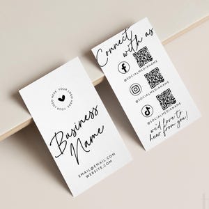 May include: Two white business cards with black text. One card reads "Business Name" and includes contact information. The other card says "Connect with us" and features social media icons with QR codes. The cards are on a neutral background.