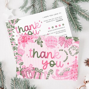 May include: Two pink and green Christmas thank you cards with festive illustrations of ornaments, gifts, and a sleigh. The cards have the words "thank you" in a playful font. The background includes pine branches and decorative elements.