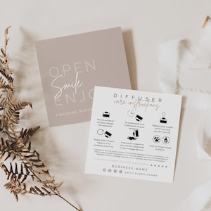 May include: Two square cards with printed text and icons. One card is taupe with the text OPEN. Smile ENJOY. The second card is white with black text titled DIFFUSER care instructions, featuring icons for usage, safety, and social media icons.