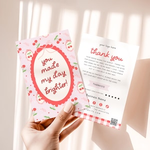 Könnte beinhalten: Rosa-weiße Dankeskarten mit Kirschmuster. Eine Karte zeigt "you made my day brighter!" in einem roten Oval. Die andere Karte sagt "thank you" mit Platz für Logo und Geschäftsinformationen.