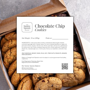May include: A box of chocolate chip cookies from The Sunny Spoon Bakery. The label indicates a net weight of 280g. The box is open, revealing several golden-brown cookies.