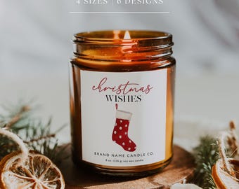 May include: A lit soy wax candle in a glass jar with a label that reads "Christmas Wishes." The label features a red stocking with white polka dots. The candle sits on a wooden base, surrounded by dried orange slices and greenery.