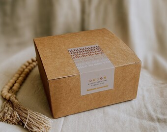 May include: A square brown cardboard box featuring a rectangular label with the repeated text hi, hello, and nice to see you. The label includes social media icons, the text @SOCIALMEDIANAME, WEBSITE.COM, and business name here.