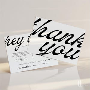 May include: Two white rectangular thank you cards with black text. The front card features large black cursive text reading "thank you". The back card displays "hey there", "YOUR SUPPORT MEANS EVERYTHING", "THANKYOU10", and "xo, monica".