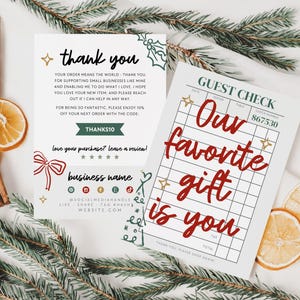 Puede incluir: Imagen festiva con dos tarjetas con texto, rodajas de naranja secas, palitos de canela y ramas de hoja perenne. Una tarjeta dice "gracias" y la otra dice "Nuestro regalo favorito eres tú."