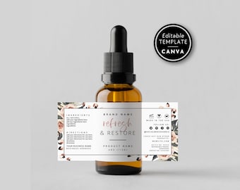 Op de afbeelding: Een amberkleurige glazen druppelfles met een zwarte dop en een wit rechthoekig etiket met bloemillustraties, de tekst "refresh & RESTORE", "4OZ (113G)" en tijdelijke aanduidingen voor ingrediënten en gebruiksinstructies.