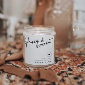 May include: A white soy wax candle in a glass jar with a label that reads "Honey & Coconut". The candle is hand-poured and is 8 ounces (227 grams).