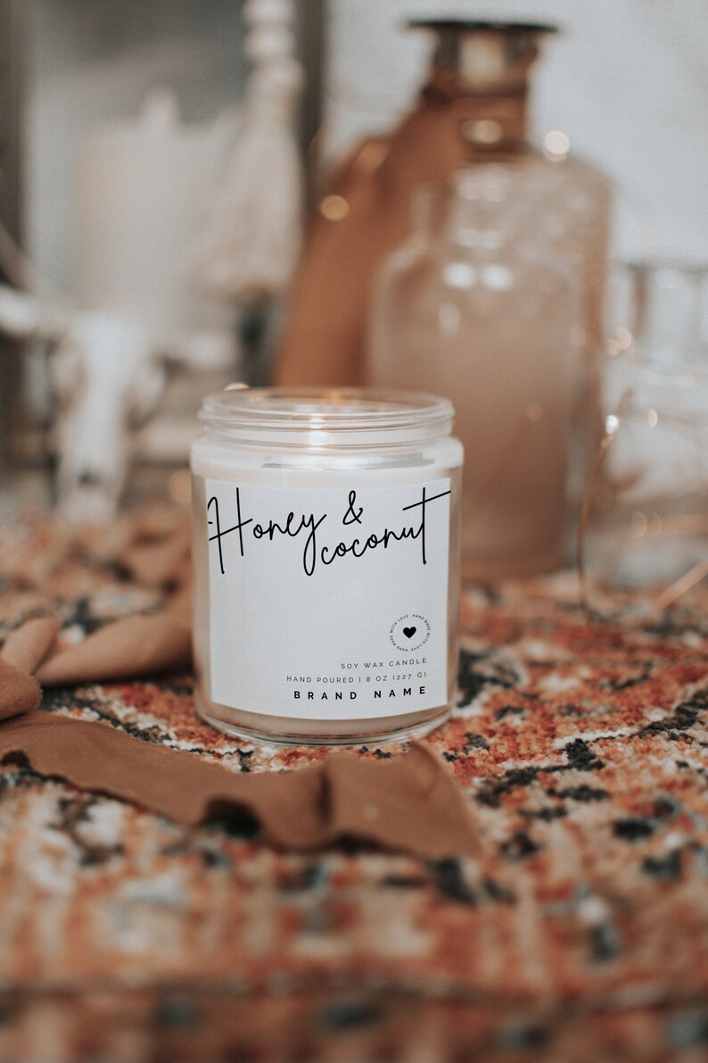 May include: A white soy wax candle in a glass jar with a label that reads "Honey & Coconut". The candle is hand-poured and is 8 ounces (227 grams).