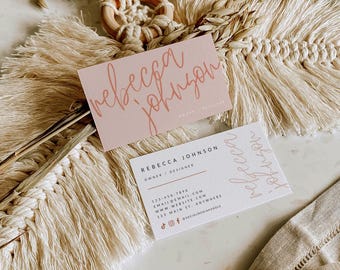 May include: Two rectangular business cards featuring the name Rebecca Johnson. One card is light pink with script text, the other is white with black sans-serif text including contact details, a website, and social media icons.