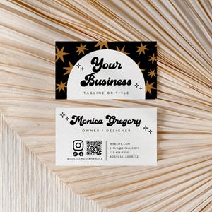 May include: Two rectangular business cards. The top card is black with gold stars and a white semi-circle containing the text Your Business and Tagline or Title. The bottom card is white with the text Monica Gregory, Owner | Designer, social media icons, a QR code, and contact details.