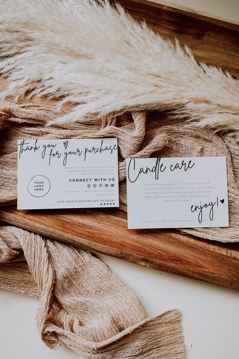 May include: Two white cards with black text on a wooden surface. The first card says "Thank you for your purchase" and has a heart symbol. The second card says "Candle care" and includes instructions for burning candles. Both cards have a logo and social media information.