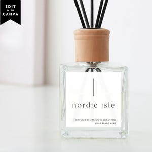 May include: A clear glass reed diffuser bottle with a light wood cap and black reeds. The white square label features the text nordic isle, DIFFUSER DE PARFUM, 6OZ. (170G), and YOUR BRAND HERE. A black tag in the corner reads EDIT WITH CANVA.