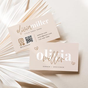 May include: Two business cards with the name "olivia miller" in a modern font. The cards are a light beige colour with social media icons, a QR code, and contact information. The cards are arranged on a neutral background.