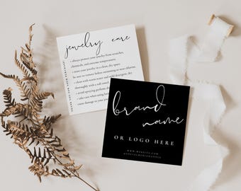 May include: A white square jewelry care card with black text and a black square brand name card with white text. The cards are displayed alongside a dried brown fern leaf and a piece of white ribbon on a light neutral surface.