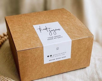May include: A square brown cardboard shipping box featuring a white rectangular label on the top. The label displays the text thanks. gorgeous, YOUR ORDER MADE MY DAY!!, your logo, social media icons, a website placeholder, and BRAND NAME HERE.