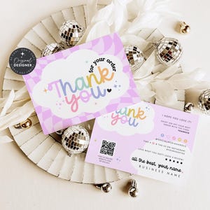Könnte beinhalten: Zwei pastellrosa "Thank You" Karten mit einem Schachbrettmuster und Regenbogen-Text, präsentiert auf einem dekorativen Teller mit Discokugel-Ornamenten und weißen floralen Akzenten. Die Karten enthalten einen QR-Code und Social-Media-Informationen.