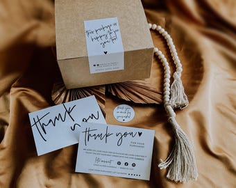 Può includere: Una scatola quadrata in cartone marrone con un adesivo bianco con la scritta This package is happy to see you too, due biglietti di ringraziamento bianchi con testo nero e una collana di perline di legno chiaro con due nappe.
